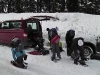 Gruppe vor einem Auto schnallt sich die Schneeschue an
